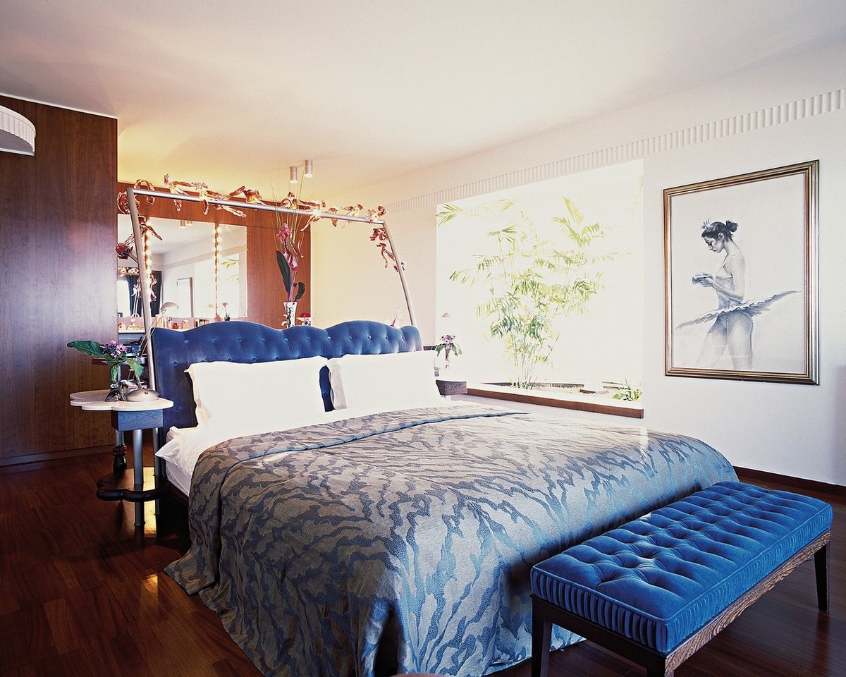 Velká postel s modrými doplňky dodává ložnici prostor pro romantické snění.