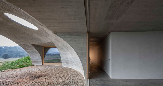 Dům z betonu díky zahloubení pod povrch prakticky splývá s krajinou