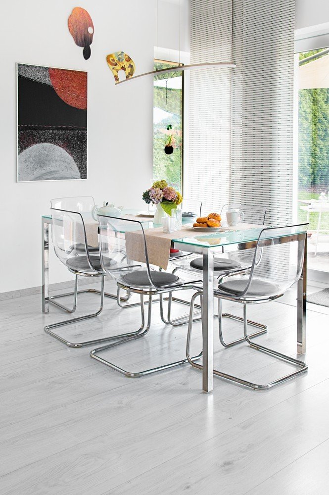 Stůl se skleněnou deskou a průhledné židle nechají opticky vyniknout umění na stěně v jídelním koutě.