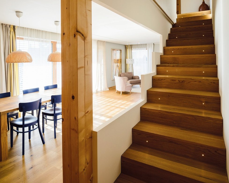 Architektonicky zajímavě řešené dřevěné schodiště s bodovým osvětlením opticky zvětšuje prostor jídelny.