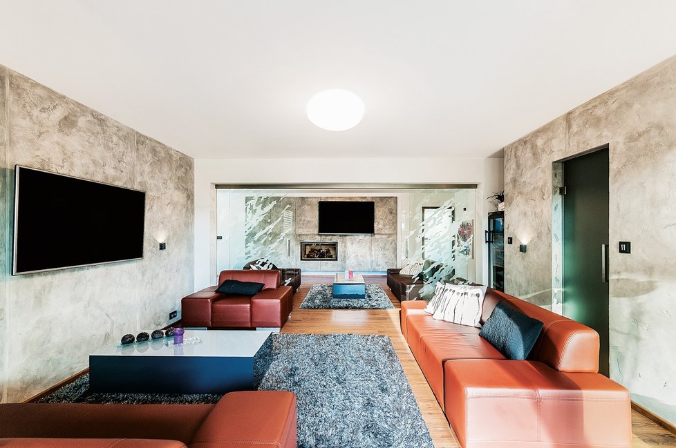 Obývací pokoj je rozdělen pomocí posuvné skleněné stěny na dvě části a je srdcem celého domu