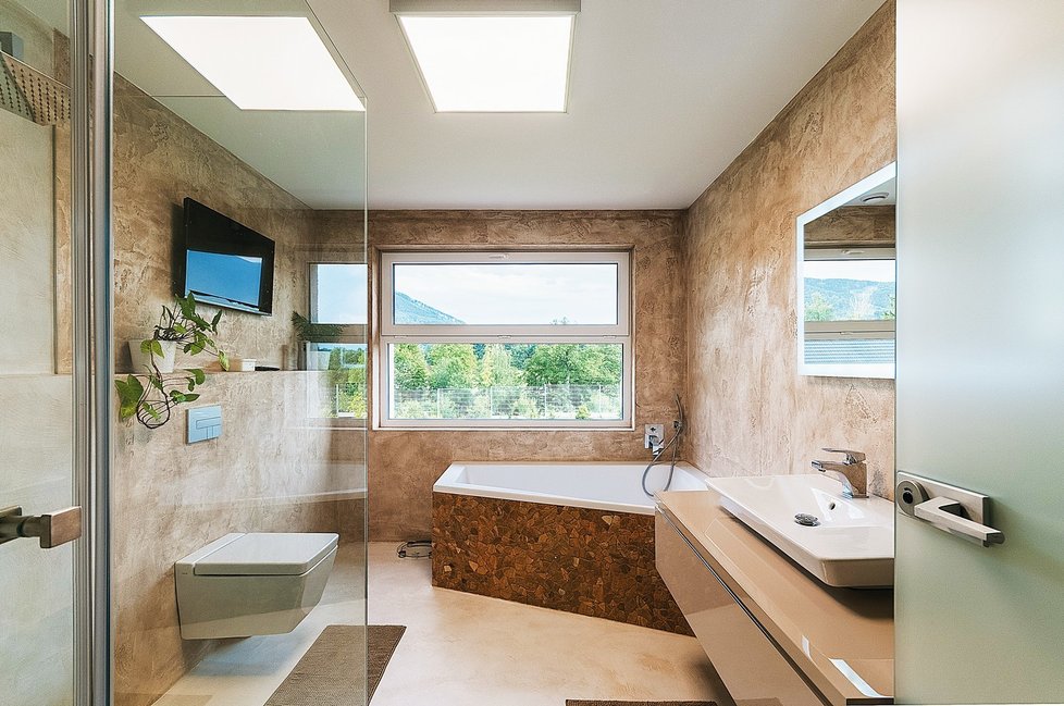 Namísto dlažby je na podlahách i v koupelnách domu využita moderní betonová stěrka probarvená do různých odstínů šedé a béžové