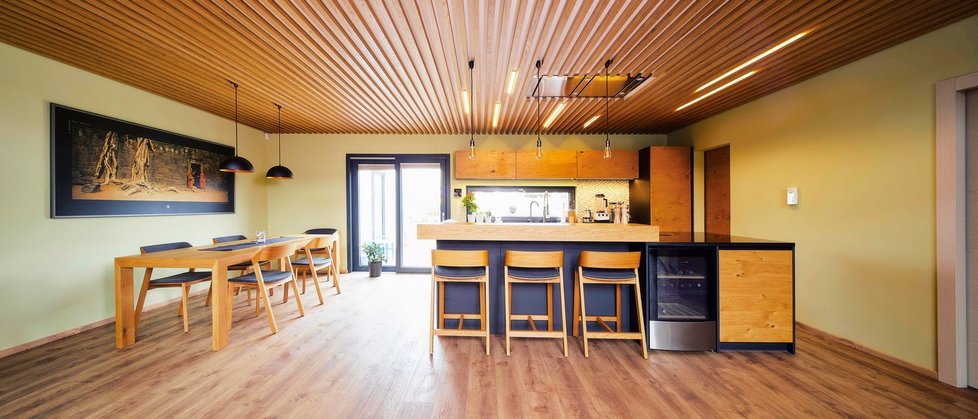 Pod galerií je umístěna kuchyň s jídelním koutem. Masivní kuchyňská linka na míru ladí s nasvíceným stropem i dřevěnou podlahou.