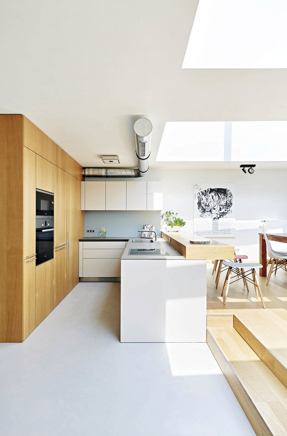 Kuchyň. Součástí dřevěného boxu jsou i dveře vedoucí do spíže. Minimalistické zařízení kuchyně neruší klidnou atmosféru prostoru s jídelnou a obývákem.