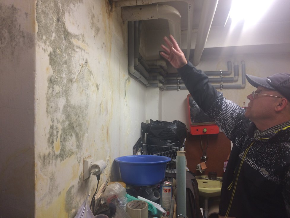 Majitel brašnářství Dalibor Tancoš ukazuje, jak mu voda z bytu plného odpadků zatopila jeho provozovnu.