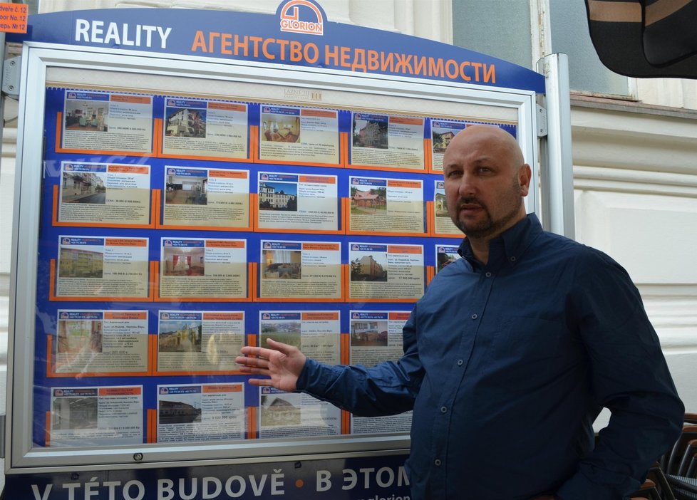 Aleksandr Mizjuk ukazuje na nabídku své realitní kanceláře.