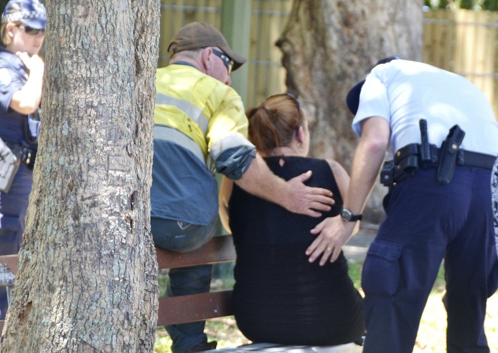 Policisté utěšují ženu poblíž domu hrůzy, ve kterém bylo nalezeno osm ubodaných dětí.