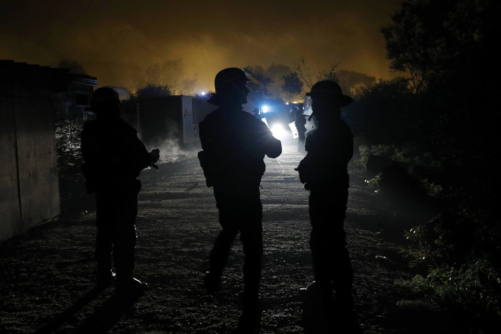 Policisté zasahují proti migrantům, kteří založili požár v táboře v Calais.