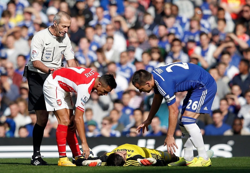 Thibaut Courtois leží na zemi po střetu s útočníkem Arsenalu Alexisem Sánchezem