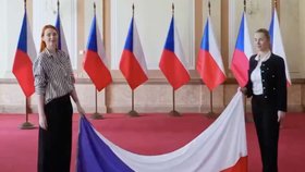 Česká vlajka dotýkající se země. Drží ji mluvčí vlády Karla Mráčková a členka PR hnutí ANO Aneta Zicklerová.