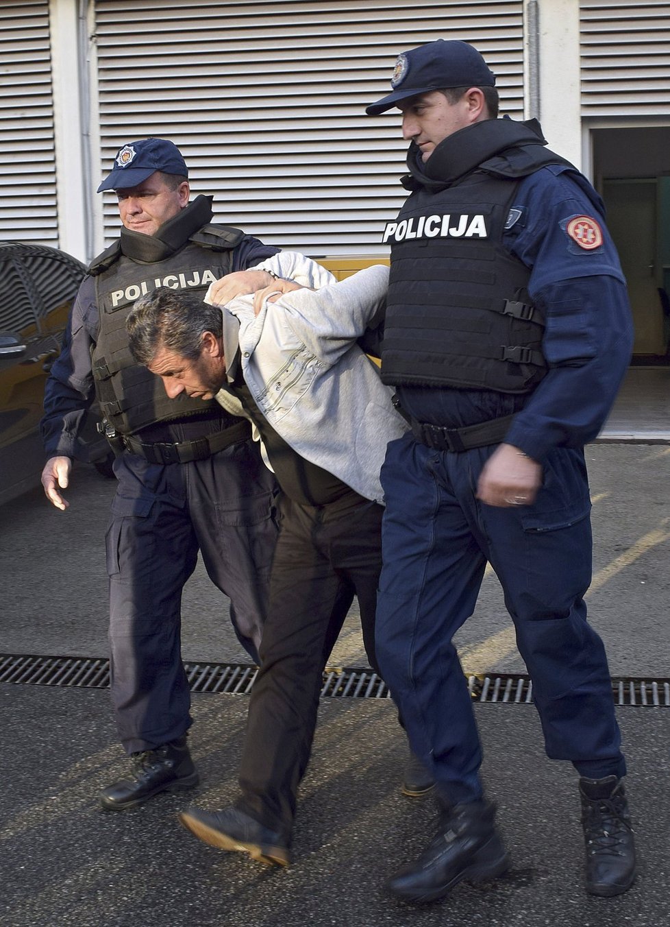 Černohorská policie eskortuje muže podezřelého z přípravy puče.