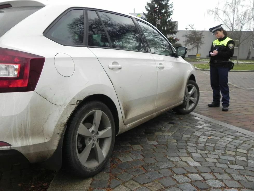 Petra řeší dopravní přestupek, auto stojí na chodníku.