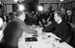 Václav Havel (vpravo) se za účasti médií zdraví s někdejším předsedou vlády Ladislavem Adamcem.