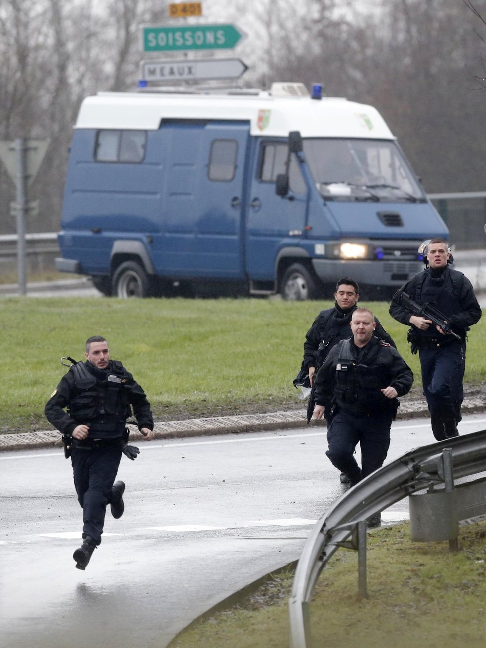 Francouzští policisté běží k budově, kde se zabarikádovali teroristé, kteří vzali rukojmí.