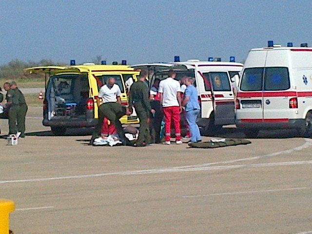 Záchranáři přenášejí vážněji zraněné pacienty na nosítkách do letadla