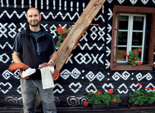 Čičmanský podnikatel Juraj Kudjak před malovanou dřevěnicí, se svými výrobky v rukou