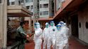 Policie v ochranném oděvu čeká na evakuaci obyvatel po vypuknutí nového koronaviru v Hongkongu