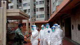 Policie v ochranném oděvu čeká na evakuaci obyvatel po vypuknutí nového koronaviru v Hongkongu.