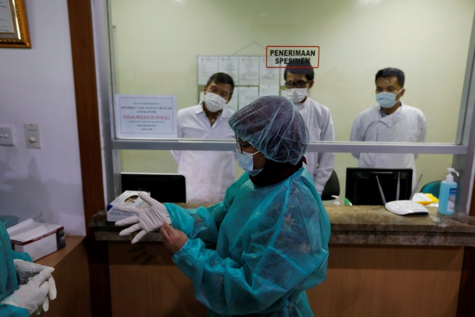 Novináři s ochrannými obleky uvnitř výtahu, když se připravují na mediální návštěvu Laboratoria indonéského ministerstva zdravotnictví pro výzkum infekčních nemocí v Jakartě.