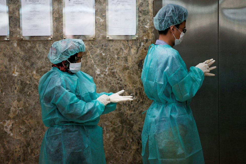 Novináři s ochrannými obleky uvnitř výtahu, když se připravují na mediální návštěvu Laboratoria indonéského ministerstva zdravotnictví pro výzkum infekčních nemocí v Jakartě