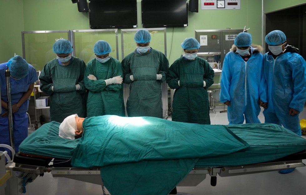 Lékařský tým a rodiče hledí na dítě před odebráním jeho orgánů.
