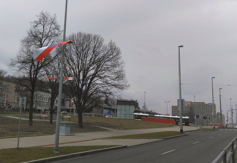 Sloup s veřejným osvětlením na Evropské a zdevastované vlajky