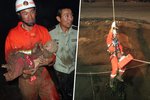 Čínští záchranáři vynáší dívku z kráteru, do kterého spadla po propadu vozovky.