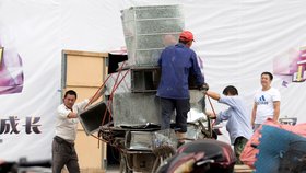 Čínští dělníci nakládají hliníkové ventilační skříně.