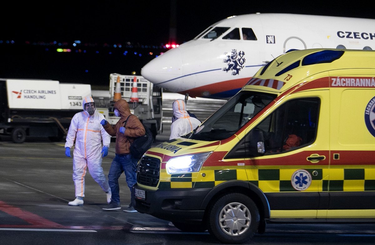 Češi a Slováci z Wu-chanu přistáli v Praze. Personál ve skafandrech je přesouvá do sanitek, s opatrností se zachází i s jejich zavazadly (3.2.2020)