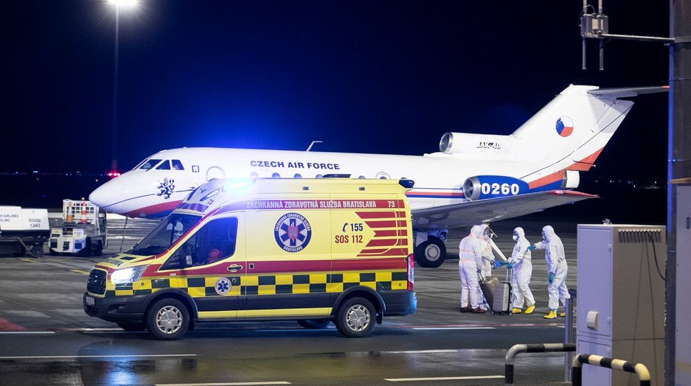 Češi a Slováci z Wu-chanu přistáli v Praze. Personál ve skafandrech je přesouvá do sanitek, s opatrností se zachází i s jejich zavazadly (3.2.2020)