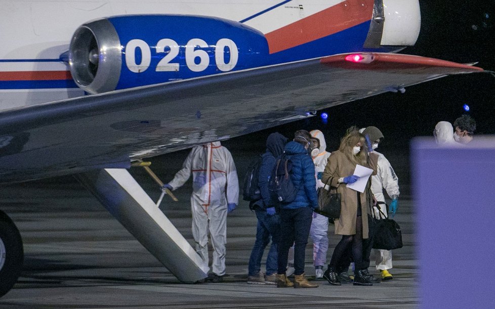 Češi a Slováci z Wu-chanu přistáli v Praze. Personál ve skafandrech je přesouvá do sanitek, s opatrností se zachází i s jejich zavazadly (3.2.2020)