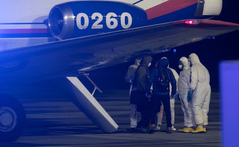 Češi a Slováci z Wu-chanu přistáli v Praze. Personál ve skafandrech je přesouvá do sanitek, s opatrností se zachází i s jejich zavazadly (3. 2. 2020)