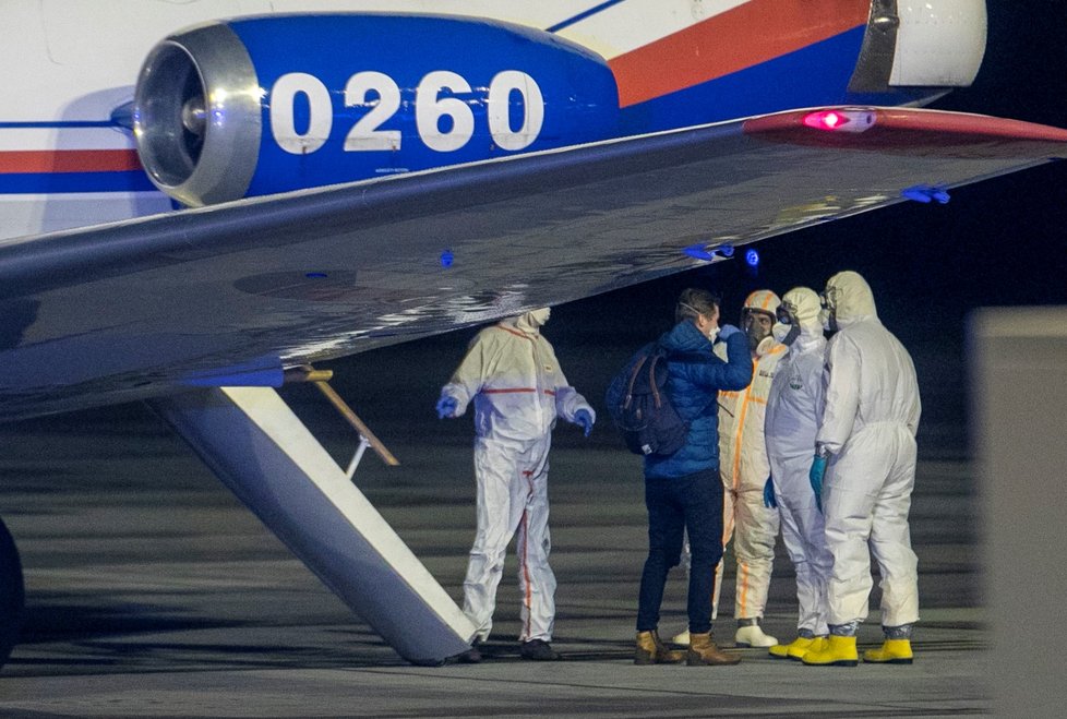 Češi a Slováci z Wu-chanu přistáli v Praze. Personál ve skafandrech je přesouvá do sanitek, s opatrností se zachází i s jejich zavazadly (3.2.2020)