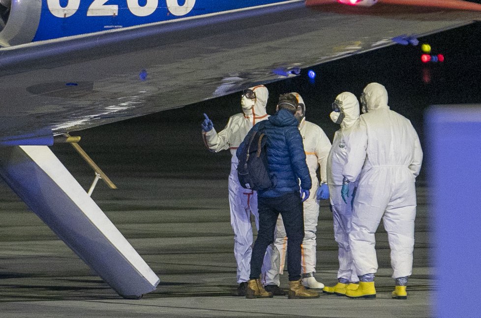 Češi a Slováci z Wu-chanu přistáli v Praze. Personál ve skafandrech je přesouvá do sanitek, s opatrností se zachází i s jejich zavazadly (3. 2. 2020)