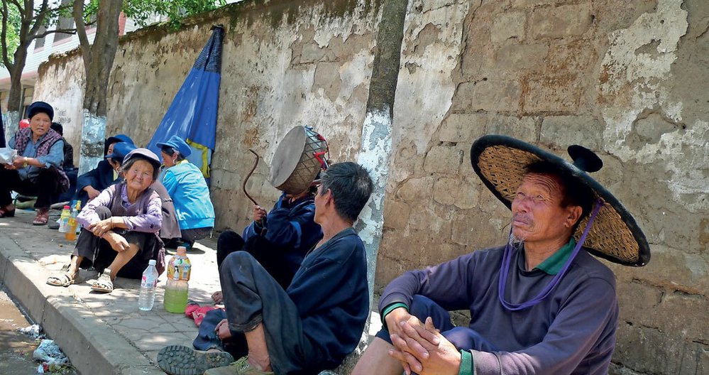 Srocení kněžích a šamanů na místním trhu v okrese Pu-tchuo (Butuo). Průměrná cena za jejich služby je 25 jüanů (tj. zhruba 80 Kč).