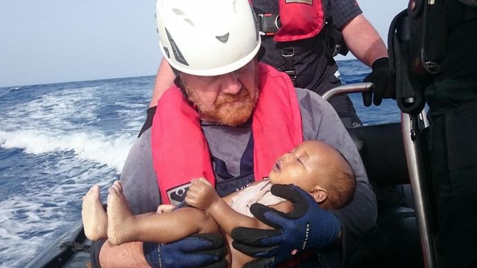 Člen humanitární organizace Sea-Watch drží v ruce utonulé dítě