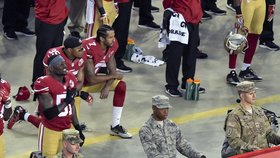 Quarterback Colin Kaepernick (uprostřed) a  jeho spoluhráči klečí během hymna na kolenou.