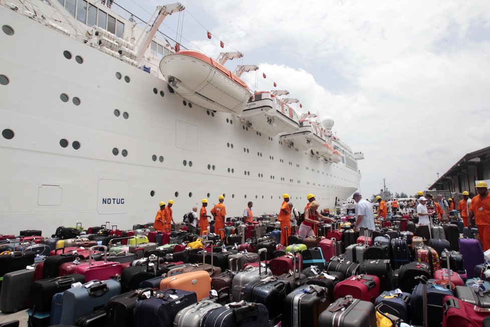 Přístavní dělníci pomáhájí vykládat zavazadla z porouchané lodi