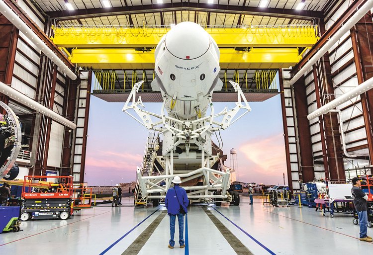 Falcon 9 a Crew Dragon při přípravě k prvnímu letu. Raketa je na startovací komplex dopravena ve vodorovné pozici