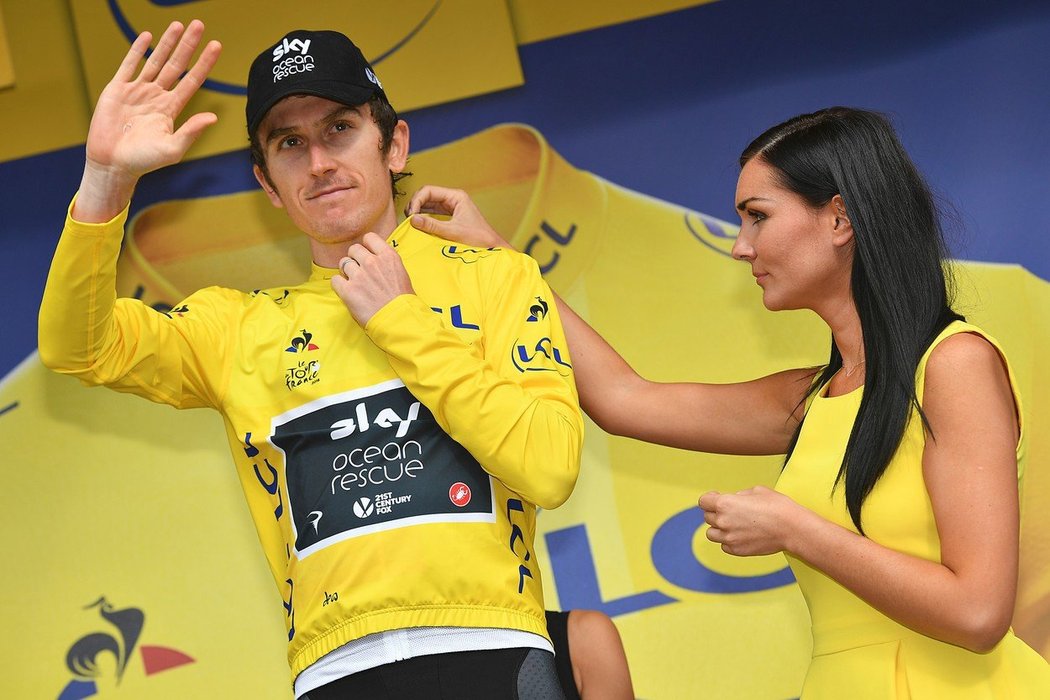 Geraint Thomas si obléká žlutý dres, pomáhá mu hosteska