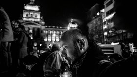 Černobílá fotografie zachycuje muže, který rozsvěcí svíčku na jednom z pietních míst, které po smrti Havla spontánně vznikla, na Václavském náměstí v Praze.