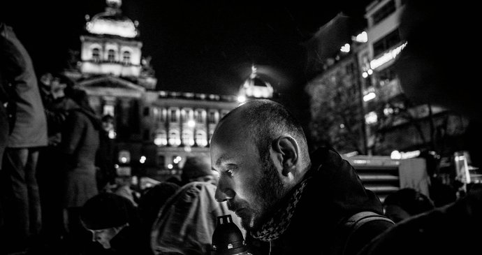 Černobílá fotografie zachycuje muže, který rozsvěcí svíčku na jednom z pietních míst, které po smrti Havla spontánně vznikla, na Václavském náměstí v Praze.