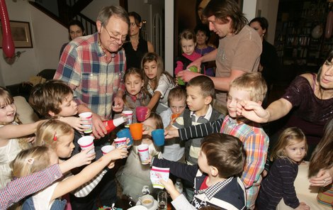 Režisér Jiří Adamec rozlévá přípitek pro hosty oslavy – dětské šampaňské. Jeho žena Jana (za ním) přihlíží.