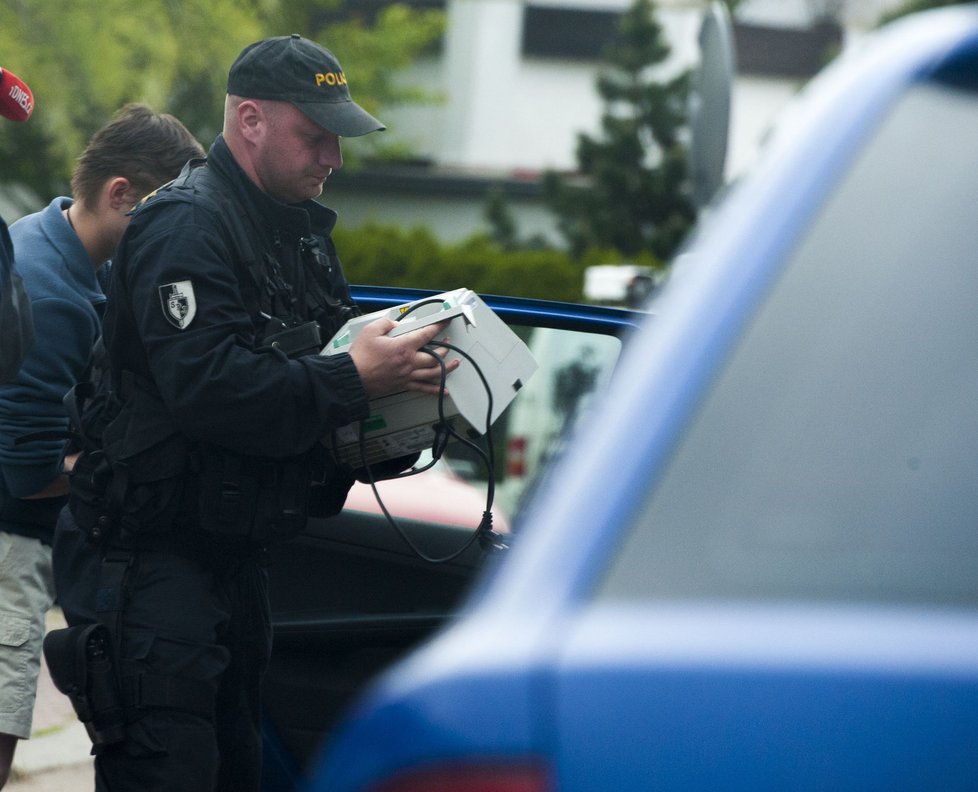 Policista nese počítadlo peněz do domu Davida Ratha v Hostivicích