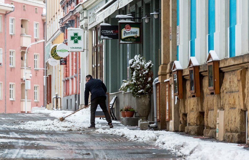 Muž odklízí sníh před domy v centru Děčína (14. 1. 2021)