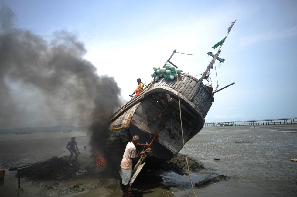 Bangladéšský rybář svou loď nepálí, ale snaží se ji opravit.