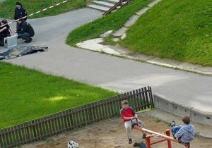 Internetem koluje fotografie z Česka, na které jsou zachyceny hrajíci si děti na hřišti. Opodál policisté ohledávají mrtvolu.