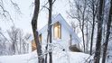 2. Dům s bílou fasádou a titanovou střechou stojí v zalesněném svahu v kanadském Quebecu.