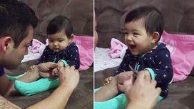 Holčička předstírá pláč, když jí táta stříhá nehty.