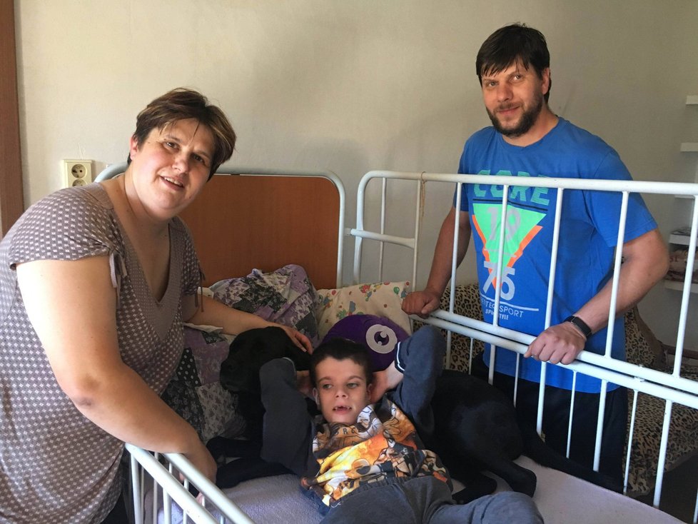 Eva a Miroslav Směšní s postiženým synkem Filipem, který se opírá o asistenčního psa Boru.
